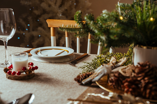 istock Acogedor entorno de mesa de Navidad, decorado con ramas de pino y mantel rústico en la sala de estar de fondo iluminado por el árbol casero 1282140774