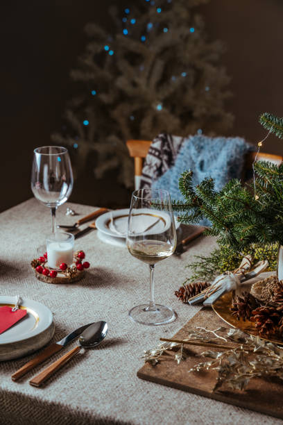 istock Homely christmas table setting, decorated with pine branches and rustic tablecloth in the living room of home tree lit background 1282140775