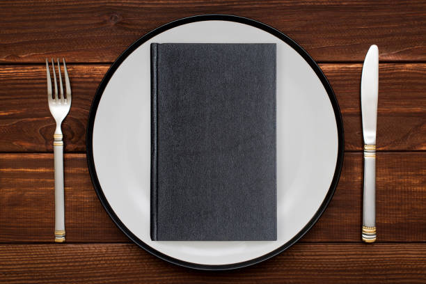 istock Book on plate with knife and fork. Concept image of a book as main course 1282141368