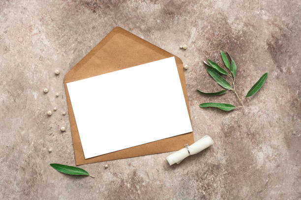 istock Blank card mockup on brown envelope, engagement ring and olive branches. Female wedding invitation card. Top view, flat lay. 1282142023