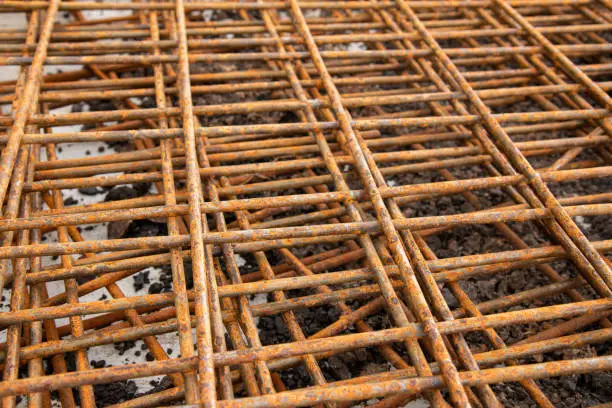 The rusty steel grid in pattern,Rusty construction metal mesh for  road infrastructure  metal rebar for construction,Sites Soak and Rust,on Soil road construction.