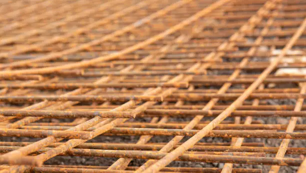 The rusty steel grid in pattern,Rusty construction metal mesh for  road infrastructure  metal rebar for construction,Sites Soak and Rust,on Soil road construction On a blurred background.