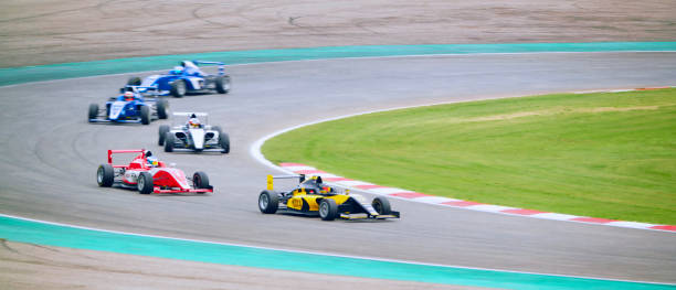 Racing drivers driving open-wheel single-seater racing car cars on racing track.