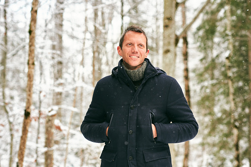 Outdoor winter portrait of middle age man in snowy forest, wearing jacket