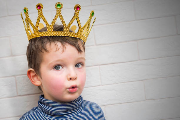 Child with a golden crown on his head against a brick wall background
