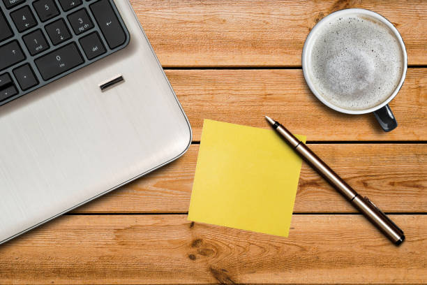 istock Laptop keyboard, empty yellow adhesive paper, pen and coffee cup on desk background 1282147042