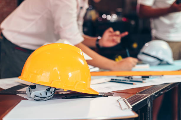 istock safety helmets  on the table at site construction. Architect, Engineer and businessman  read  planning background. 1282149161