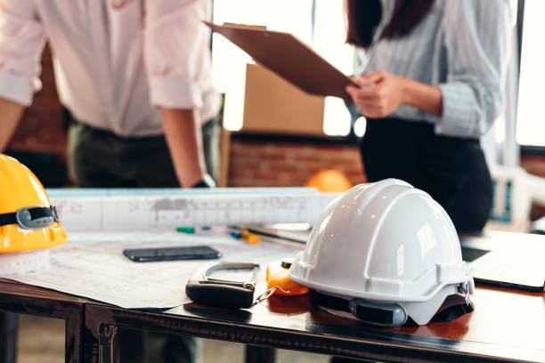 istock safety helmets  on the table at site construction. Architect, Engineer and businessman  read  planning background. 1282151618