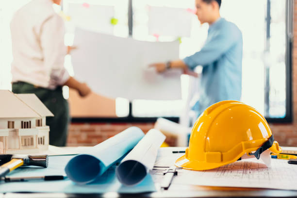 istock safety helmets  on the table at site construction. Architect, Engineer and businessman  read  planning background. 1282151785