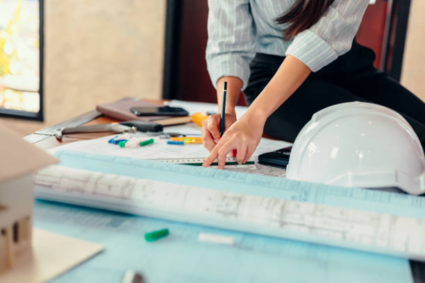 mujer ingeniera leer dibujo impreso azul en el lugar de trabajo de la mesa en la construcción del sitio de la habitación. concepto de plan de arquitecto de ingeniero. - hardhat construction men handshake fotografías e imágenes de stock