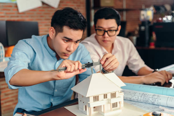 istock Engineering hands hold vernier caliper working and checking house model scale between meeting with businessman and businesswoman. 1282152356