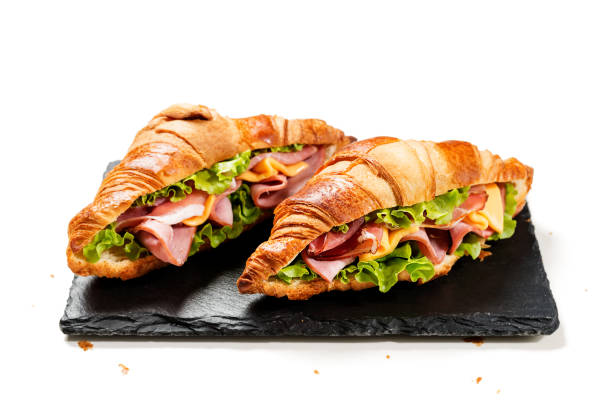 свежие сэндвичи с круассанами с ветчиной, сыром и салатным листом, изолированные на белом фоне - croissant morning white breakfast стоковые фото и изображения