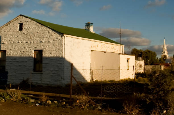 um velho celeiro em sutherland com a igreja ao fundo - house farm brick chimney - fotografias e filmes do acervo