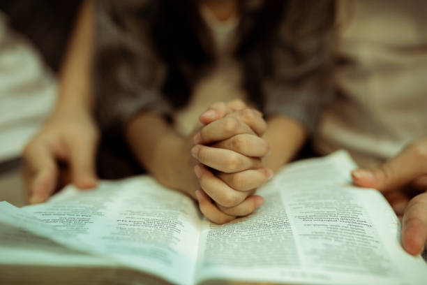 a kid reading the holy bible with guide by parents