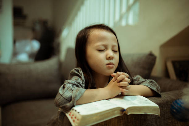 istock kid reading the holy bible and praying 1282156043