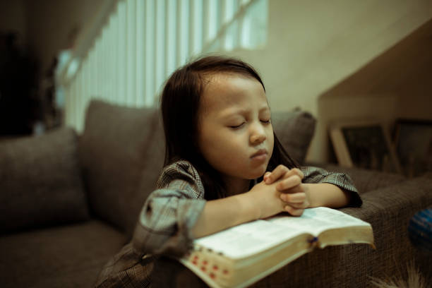 istock kid reading the holy bible and praying 1282156069