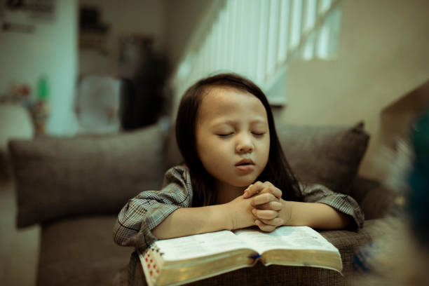kid reading the holy bible and praying