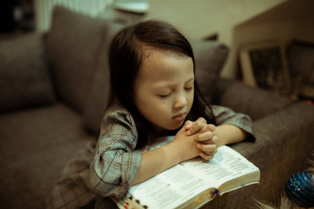 istock kid reading the holy bible and praying 1282156132