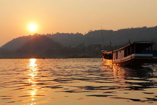 Traditional long boat on the Mekong river with sunset near Luang Prabang Laos