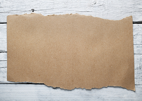 A piece of paper with torn edges of wrapping paper on the background of an old white wood texture.Background for text.