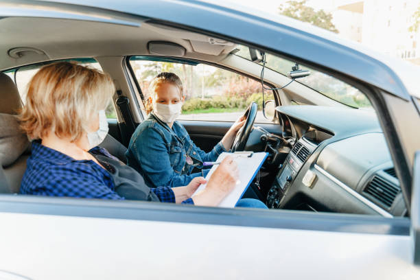 teenager avendo lezione di guida con istruttore femminile durante covid 19 - driving test foto e immagini stock