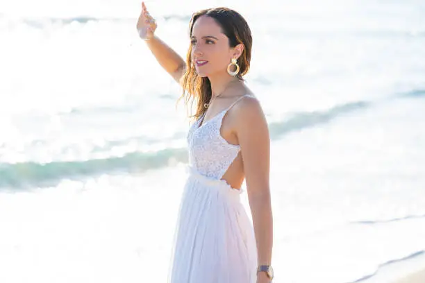 Tourist woman on the beach relaxed with white summer dress looking to the ocean