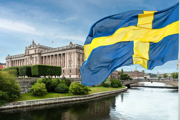 The Swedish Parliament Building The building of the Swedish Parliament (Riksdag) and the Riksbank Bridge over the Lilla Vartan Strait with the national flag of Sweden in the foreground. politics and government stock pictures, royalty-free photos & images
