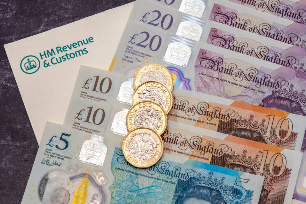 UK HM Revenue and Customs tax form and money UK HM Revenue and Customs tax form with UK banknotes and coins one pound coin photos stock pictures, royalty-free photos & images