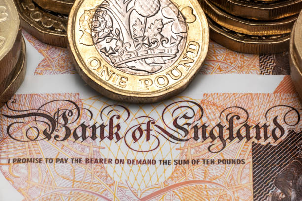 один фунт монеты размещены на банкноте - one pound coin british currency coin paper currency стоковые фото и изображения