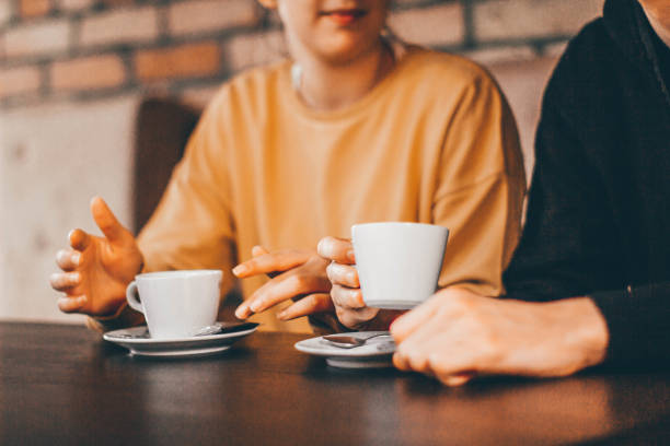 Cerrar mujer y hombre sosteniendo tazas de café en la mesa de fotos de stock - foto de stock