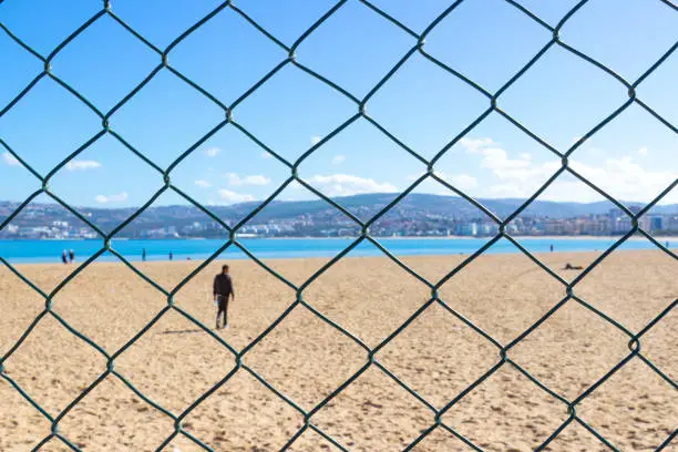 Photo of Mesh fence on municipal beach near avenue Mohamed VI at Tangier, Morocco. Themed background with a temporarily closed beach during a pandemic COVID-19