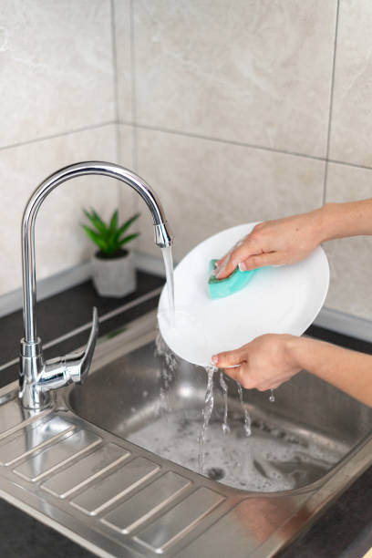istock Woman washes dishes standing in the kitchen 1282168948