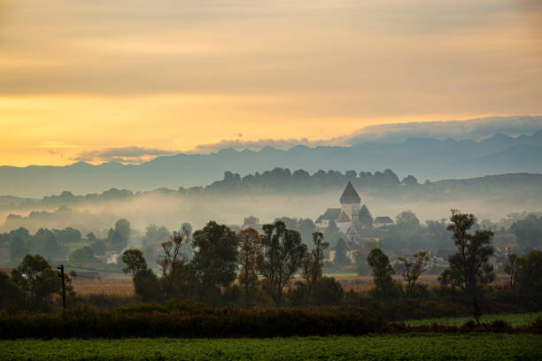 Hosman, rural Romania The fortified church of Hosman at sunrise under a thick layer of fog and smoke. Photo taken on 3rd of October 2020 near Hosman, Transylvania region, Romania. anglo saxon photos stock pictures, royalty-free photos & images