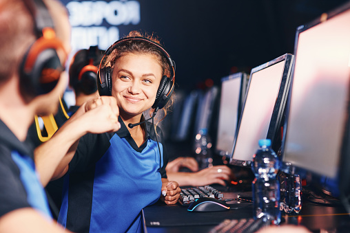 Winning. Two young happy professional cyber sport gamers giving fist bump and celebrating success while participating in eSports tournament. Online video games
