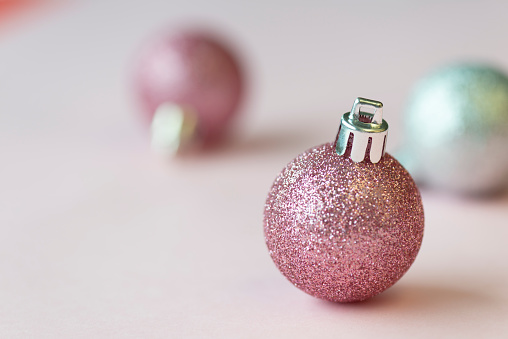 Pink and silver colored christmas baubles on pink background.