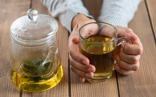 Herbal tea on wood background. Woman holding mug.