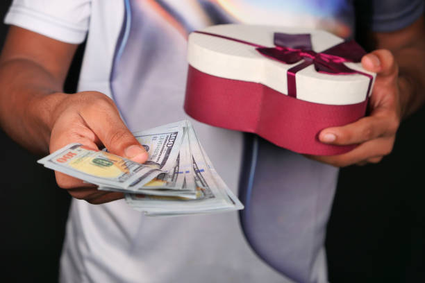 istock young man hand holding gift box and cash. 1282173799