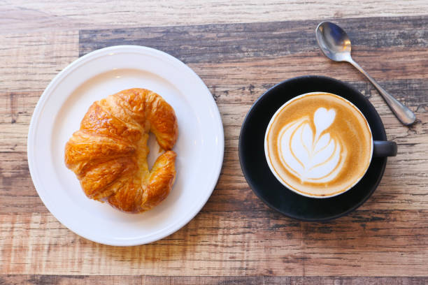 istock Coffee and croissant on wooden table, top view . 1282174368