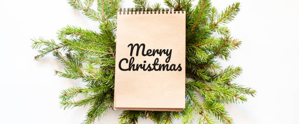istock Brown notepad lying on branches of a christmas tree with text Merry Christmas 1282175043