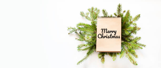 istock Brown notepad lying on branches of a christmas tree with text Merry Christmas 1282175046