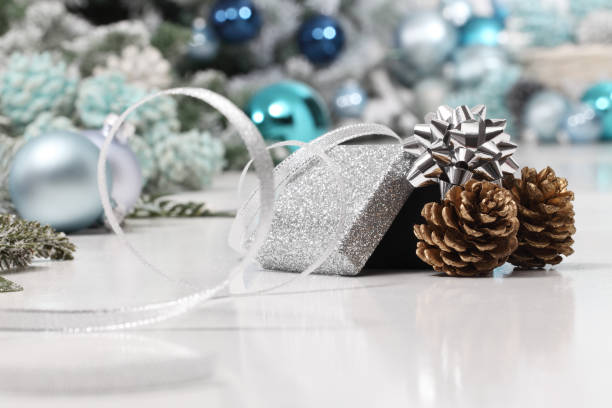 istock merry christmas background, silver gift present box with bow and ribbon, next to blue Christmas balls and pine cones, useful as a greeting card template with copy space 1282176931