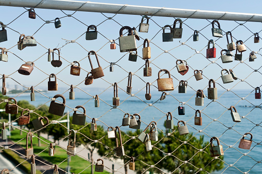 Limassol, Cyprus, October 19th, 2020: Metal love locks hanging on Cyta footbridge in front of blue sea and sky
