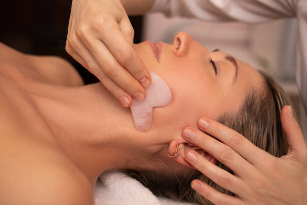 junge und schöne frau während der chinesischen traditionellen massage - gua sha. nahaufnahme foto. schönheitsbehandlung im spa-salon. anti-aging-hautpflege - massaging facial massage human face beautician stock-fotos und bilder