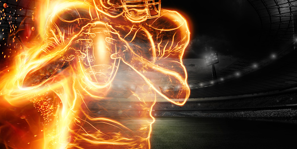 Silhouette of an American football player on fire on the background of the stadium. Concept for sports, speed, bets, American game