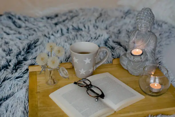 a buddha, candles and a open book with glasses on it. Fairy lights in the background