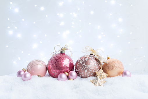 White christmas with snow - pink and golden decorative balls with lights in background. Happy Christas and holidays concept.