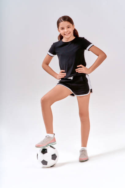 scatto a tutto campo di una simpatico adolescente sorridente alla macchina fotografica mentre si allena con il pallone da calcio, isolato su sfondo grigio in studio - beautiful looking at camera studio shot vertical foto e immagini stock