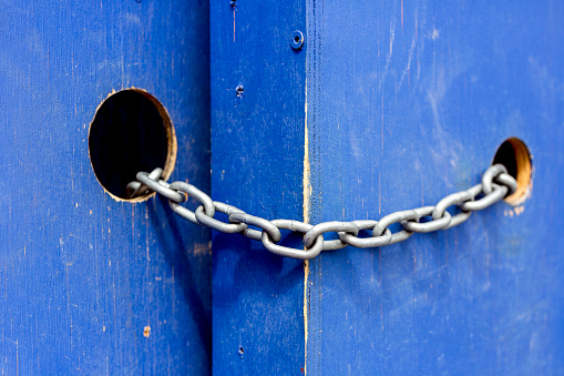 Closed blue wooden gate with metal chain, background with copy space, horizontal composition