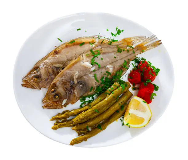 Delicious fish dish, fried roosterfish served with pickled vegetables and lemon. Isolated over white background