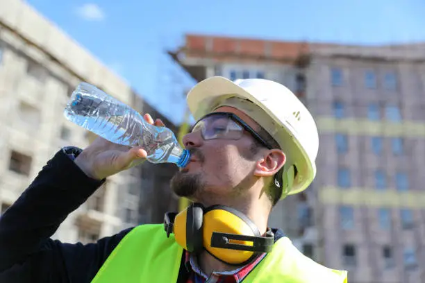 Photo of boss at construction site with bottle of water, close up